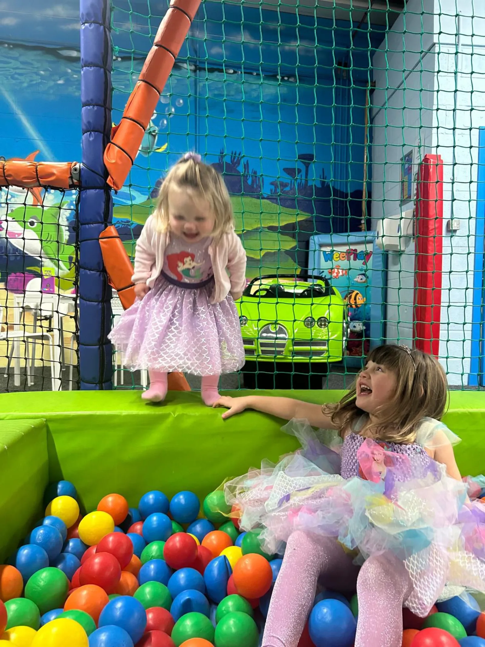 Two children laughing together in the ball pit