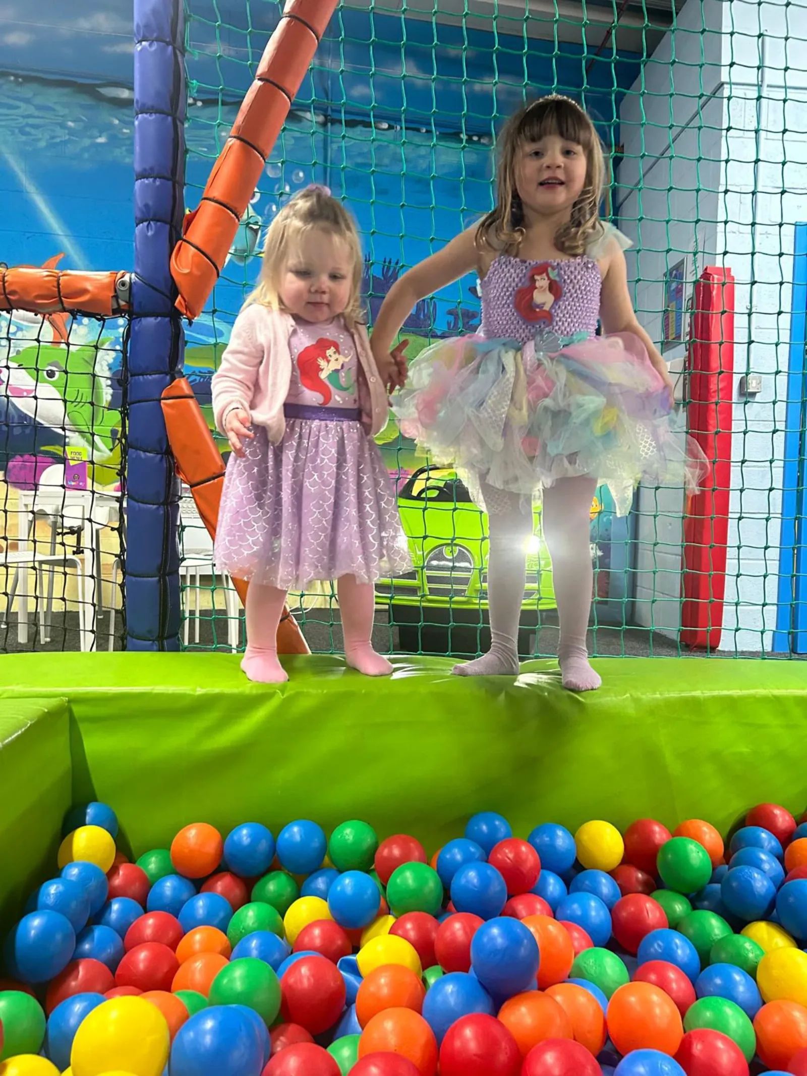 Two children in party dresses by the ball pit at a WeePlay party