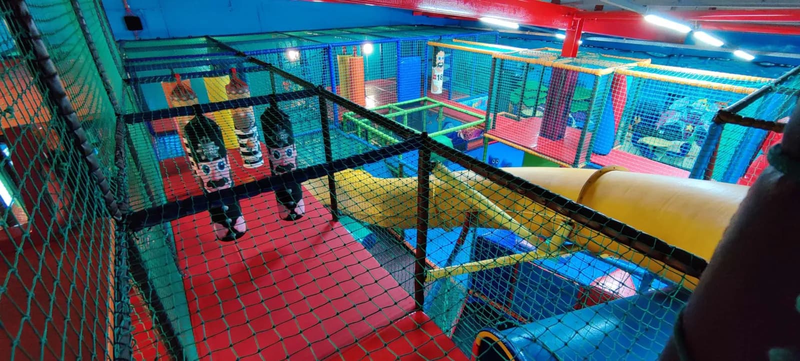 Children crossing a rope bridge high up in the soft play frame